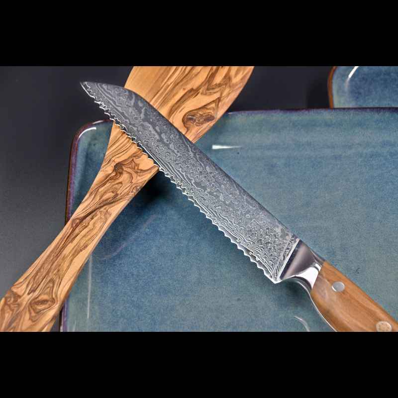 Brotmesser mit Olivenholzgriff auf hellgrünem Keramikteller - Die Messerklinge liegt auf einem Pfannenschaber aus Olivenholz auf