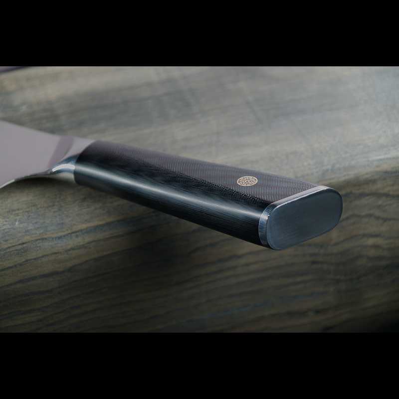 Schwarzer G10-Griff eines Damastmessers, robust und ergonomisch, in detaillierter Nahaufnahme.